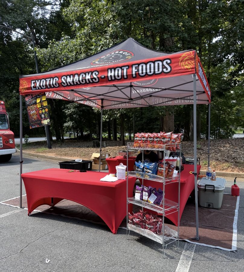 The Gas Bros tent setup: red tables, exotic snack racks and an Exotic Snacks, Hot Foods canopy
